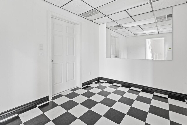 unfurnished room featuring dark tile patterned flooring and a drop ceiling