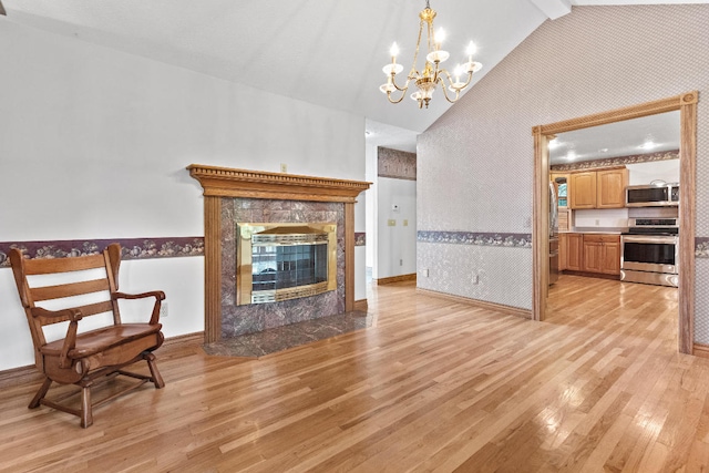 living room with a fireplace, high vaulted ceiling, light hardwood / wood-style floors, and a chandelier