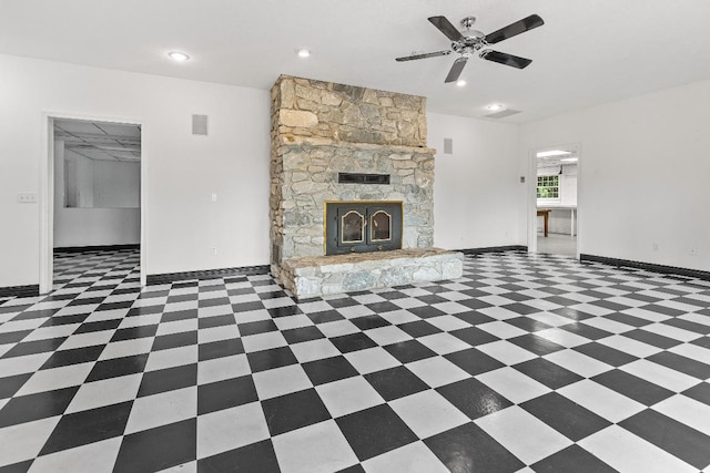 unfurnished living room with ceiling fan, dark tile patterned floors, and a fireplace