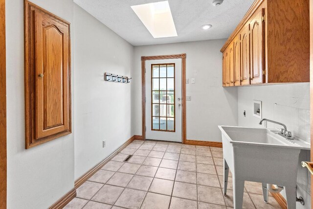 laundry room featuring a skylight, cabinets, hookup for a washing machine, a textured ceiling, and light tile patterned flooring