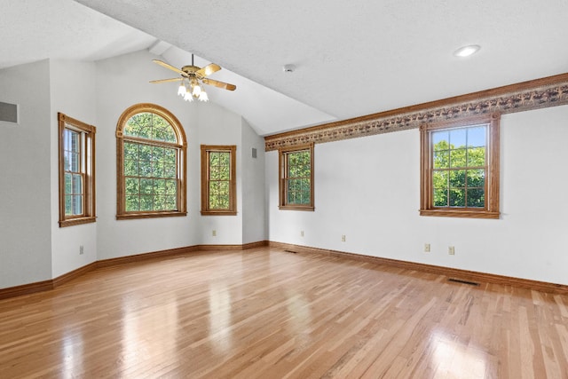 spare room with ceiling fan, light hardwood / wood-style floors, a textured ceiling, and lofted ceiling