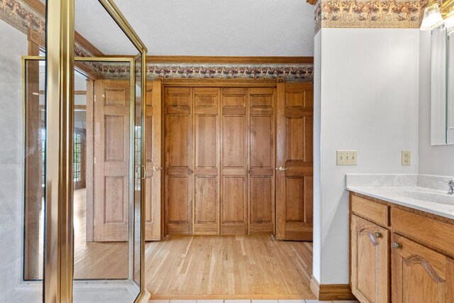 bathroom with hardwood / wood-style flooring, a textured ceiling, vanity, and walk in shower