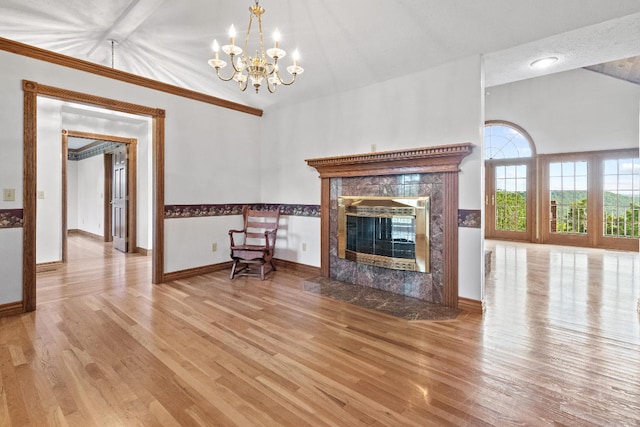 unfurnished living room with light hardwood / wood-style floors, lofted ceiling, a notable chandelier, and a fireplace