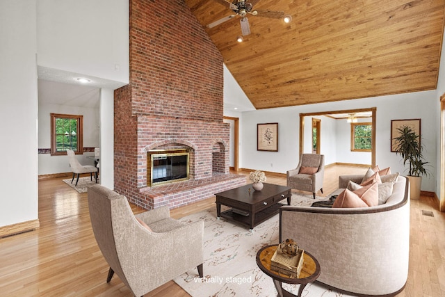 living room with ceiling fan, high vaulted ceiling, a brick fireplace, and light hardwood / wood-style floors