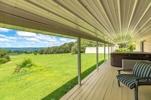 wooden deck featuring a hot tub and a lawn