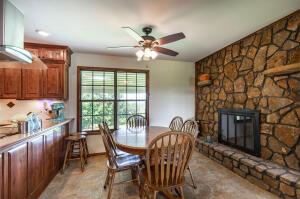 dining room with ceiling fan and a stone fireplace