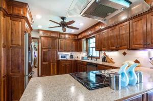 kitchen featuring white microwave, black electric stovetop, light stone counters, extractor fan, and ceiling fan