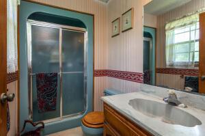 bathroom with a shower with door, toilet, and vanity