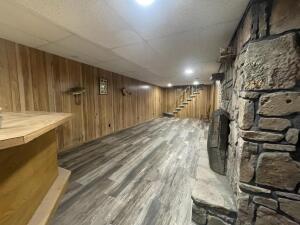 basement featuring wood walls and a stone fireplace