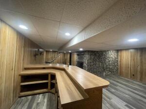 bar featuring stairway, wood walls, a drop ceiling, and wood finished floors