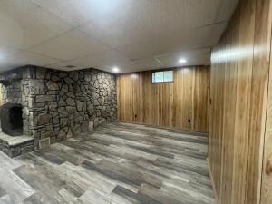 basement featuring wood walls, hardwood / wood-style floors, and a fireplace