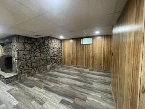 basement featuring a sauna, a stone fireplace, wood walls, and wood finished floors