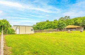 view of yard featuring fence, a pole building, and an outdoor structure