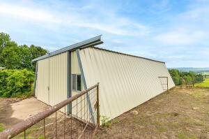 view of property exterior featuring an outbuilding, fence, and an outdoor structure