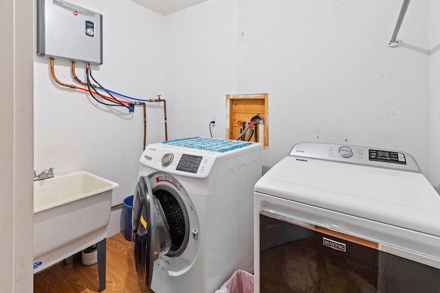 laundry area with light wood-type flooring, washer and dryer, and sink