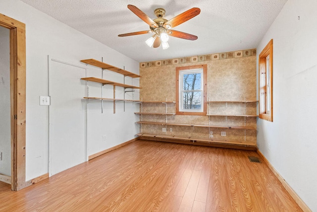 empty room with a textured ceiling, light hardwood / wood-style floors, and ceiling fan