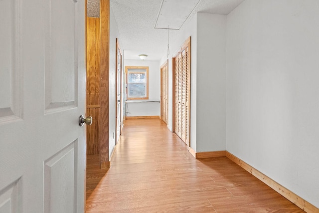 corridor featuring light hardwood / wood-style flooring and a textured ceiling