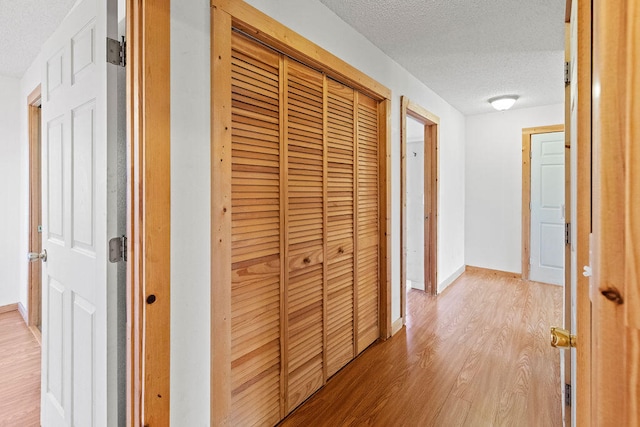 corridor featuring light hardwood / wood-style floors and a textured ceiling