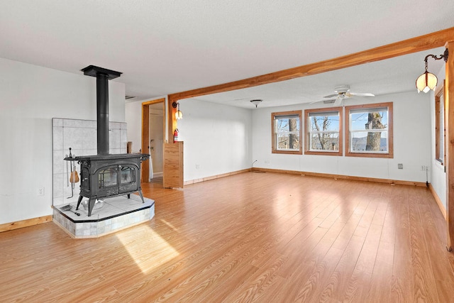 living room featuring ceiling fan, light hardwood / wood-style flooring, and a wood stove