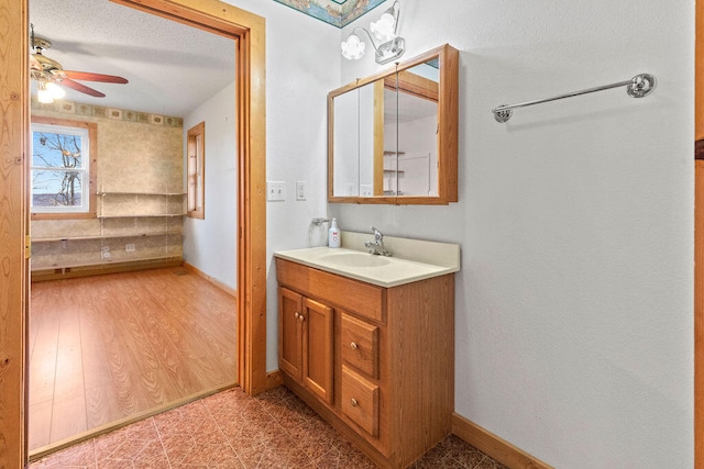 bathroom with a textured ceiling, wood-type flooring, vanity, and ceiling fan