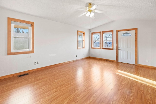 empty room with light wood-type flooring, lofted ceiling, ceiling fan, and plenty of natural light