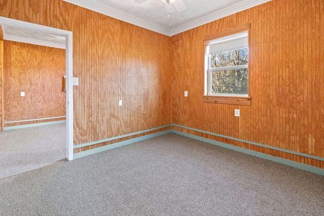 carpeted empty room with ornamental molding and wood walls