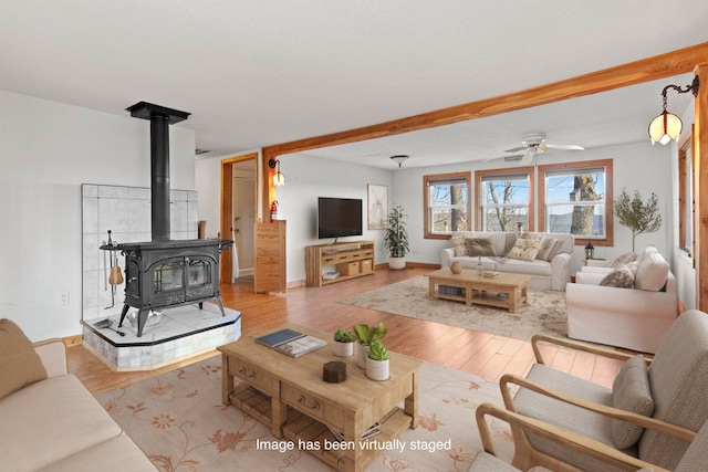 living room with light wood-type flooring, ceiling fan, and a wood stove