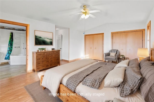 bedroom featuring ceiling fan, lofted ceiling, two closets, and hardwood / wood-style floors