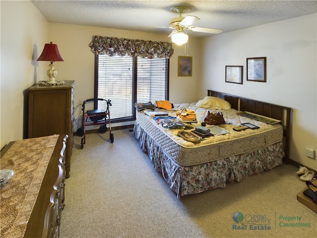 carpeted bedroom featuring ceiling fan and a textured ceiling