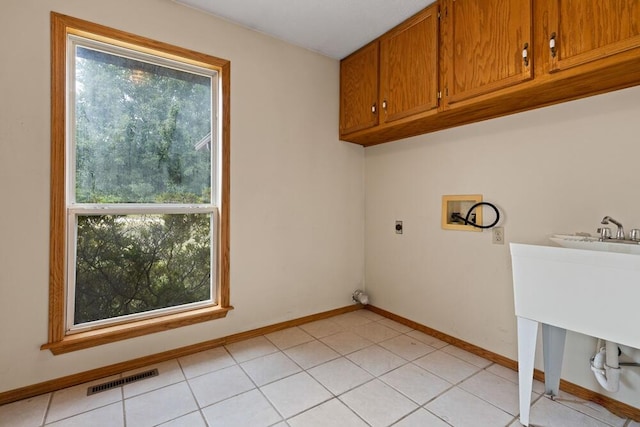 laundry area featuring washer hookup, cabinets, a healthy amount of sunlight, and light tile patterned floors