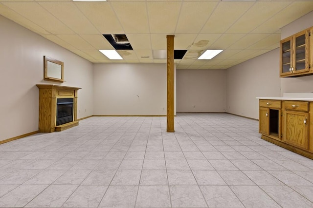 basement featuring light tile patterned floors and a drop ceiling