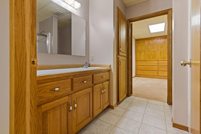 bathroom featuring a drop ceiling, walk in shower, tile patterned flooring, and vanity