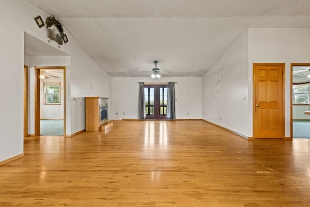 unfurnished living room featuring a wealth of natural light, ceiling fan, light carpet, and lofted ceiling