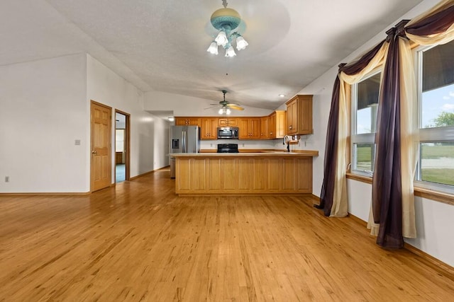 kitchen featuring appliances with stainless steel finishes, light hardwood / wood-style flooring, lofted ceiling, and kitchen peninsula