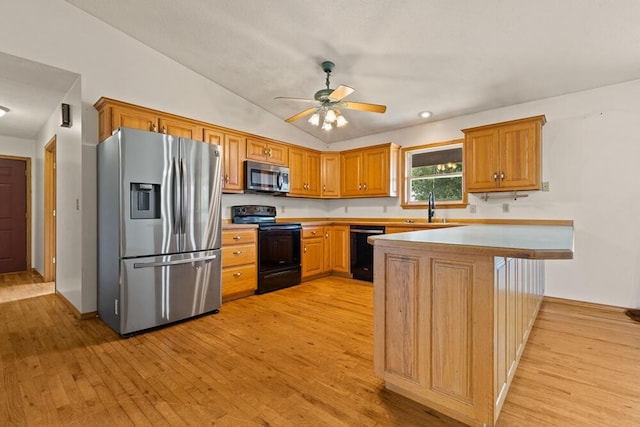 kitchen featuring light hardwood / wood-style floors, vaulted ceiling, kitchen peninsula, and black appliances