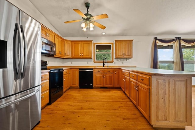 kitchen with light hardwood / wood-style floors, appliances with stainless steel finishes, vaulted ceiling, and a healthy amount of sunlight