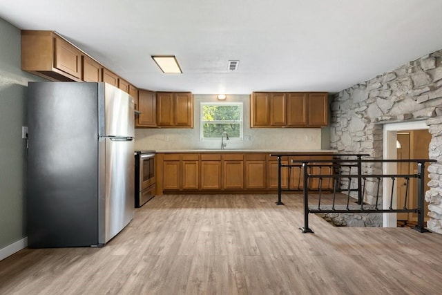 kitchen with sink, tasteful backsplash, light hardwood / wood-style flooring, and appliances with stainless steel finishes