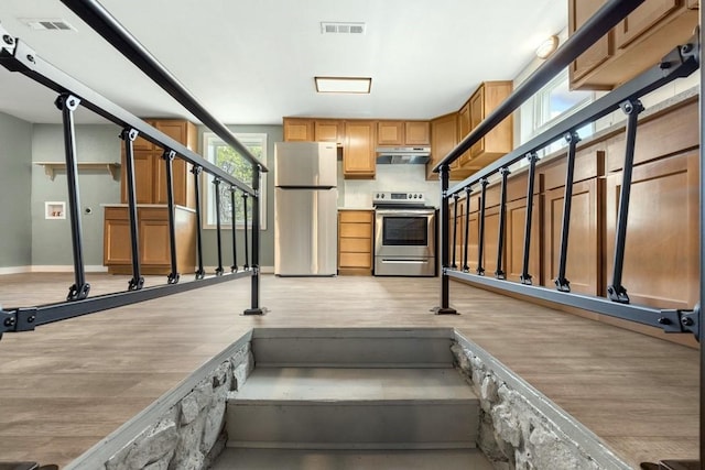 kitchen with light hardwood / wood-style floors, ventilation hood, and stainless steel appliances