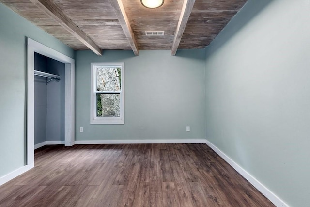 unfurnished bedroom featuring a closet, dark hardwood / wood-style flooring, beam ceiling, and wood ceiling