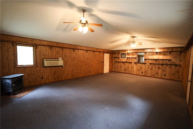 basement featuring wooden walls, a wood stove, ceiling fan, carpet, and an AC wall unit