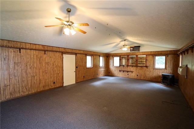 interior space with a textured ceiling, wood walls, and ceiling fan