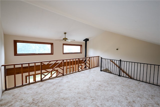 additional living space featuring a wood stove, vaulted ceiling, and light carpet