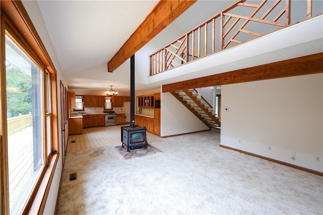 carpeted living room with beamed ceiling, high vaulted ceiling, and a wood stove