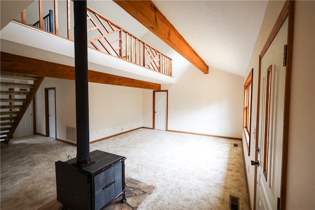 living room with lofted ceiling with beams, a wood stove, and carpet flooring