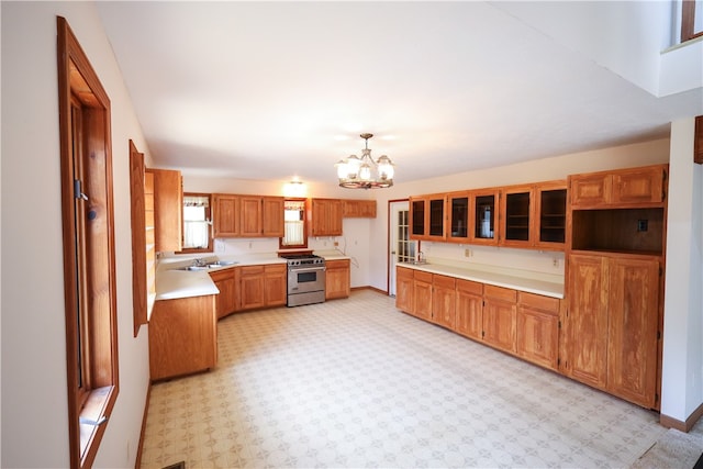 kitchen featuring pendant lighting, stainless steel gas range, an inviting chandelier, and sink