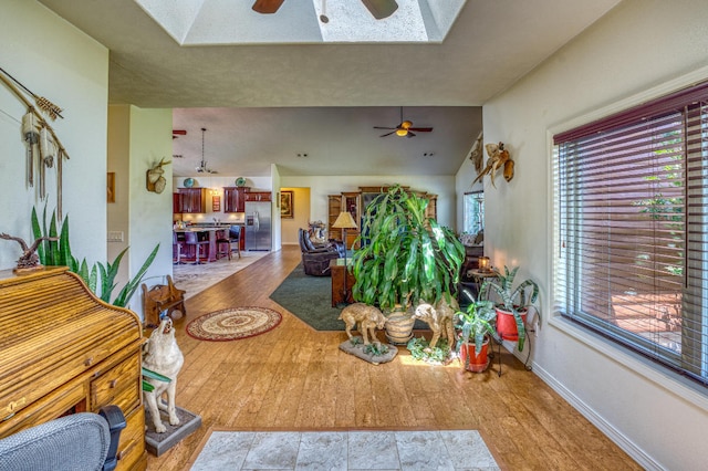 living room with ceiling fan, plenty of natural light, and light hardwood / wood-style flooring