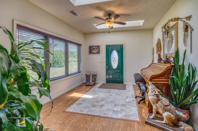 entrance foyer featuring ceiling fan, a skylight, and light hardwood / wood-style flooring