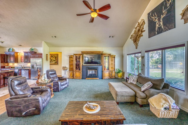 carpeted living room with ceiling fan and high vaulted ceiling