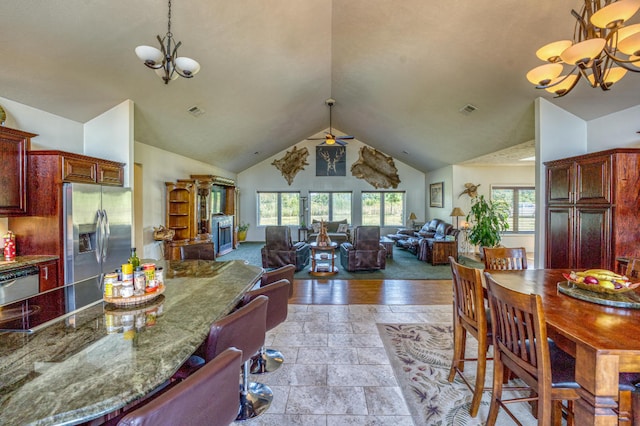 kitchen with high vaulted ceiling, decorative light fixtures, appliances with stainless steel finishes, a chandelier, and light hardwood / wood-style floors