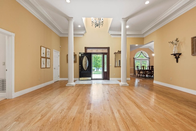 entrance foyer with light wood-type flooring, ornate columns, and crown molding